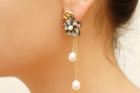 A flat lay of colourful earrings on a soft pastel background—featuring asymmetrical pairs, beaded designs, and bold shapes.