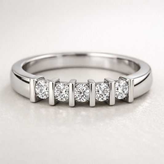 Close-up of a white gold band ring featuring seven small round diamonds set in a row on a neutral background.