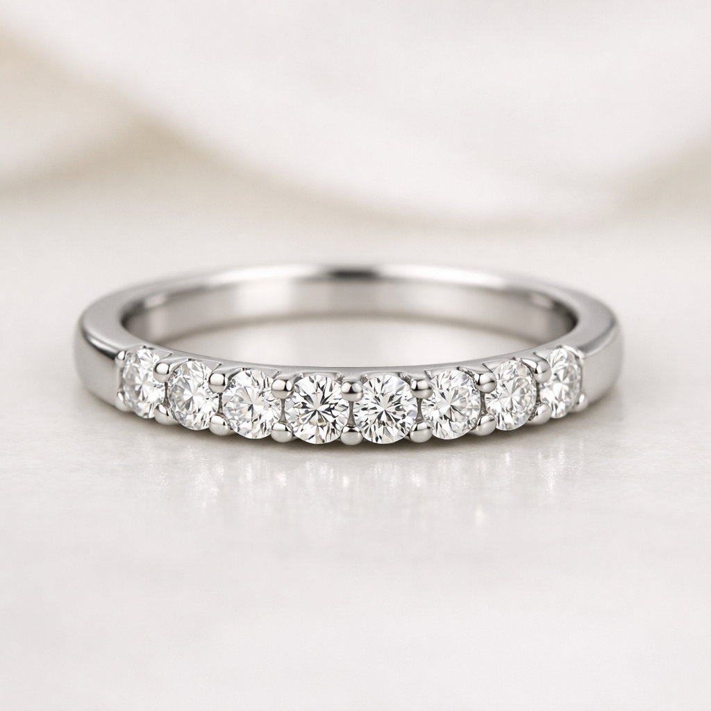 Close-up of a half‑eternity ring with diamonds across the top half of the band on a neutral background