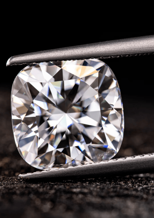 Close-up of a round brilliant diamond held by metal tweezers against a dark background.