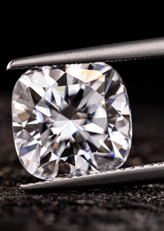 Close-up of a round brilliant diamond held by metal tweezers against a dark background.