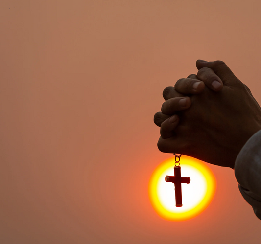 Person raying holdingva cross demonstrating faith in God