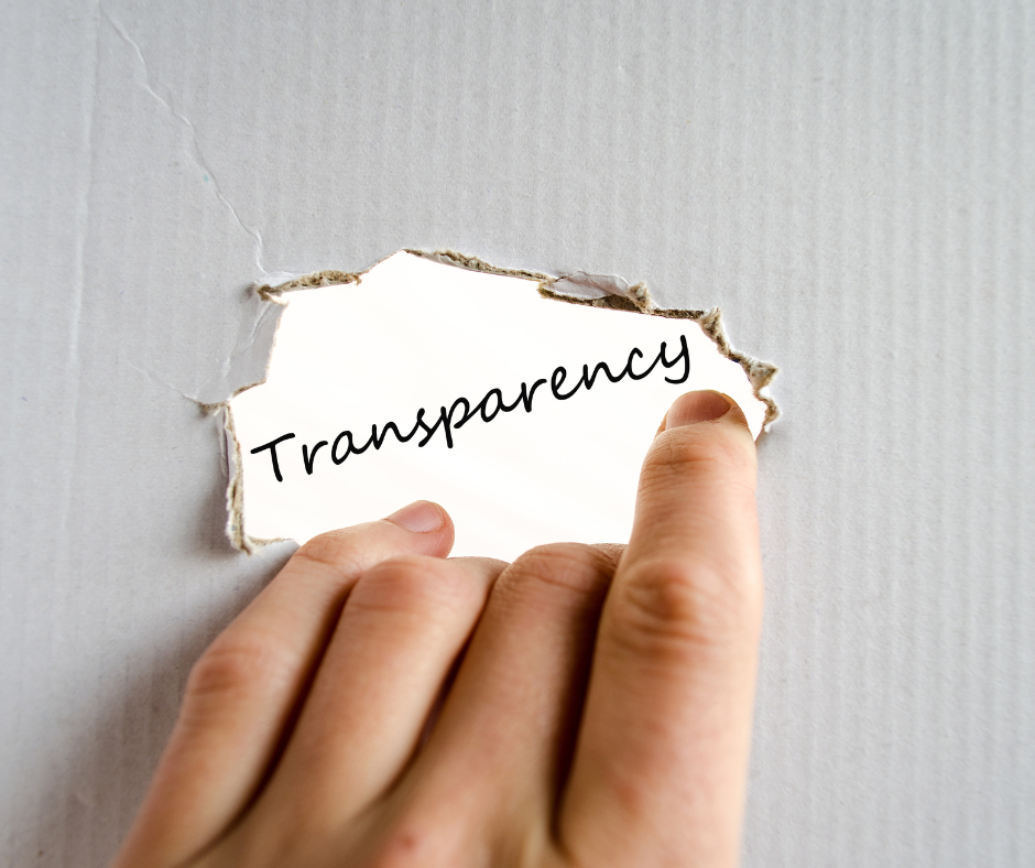 Hand revealing the word Transparency through torn paper
