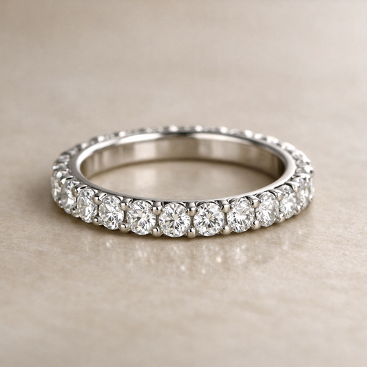 Close-up of a pavé-set eternity ring with round diamonds set in a continuous row on a white gold band, photographed on a neutral background.