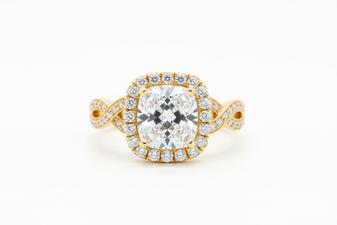 Close-up of a halo-set diamond engagement ring on a yellow gold band with a pavé halo, photographed against a neutral background under soft lighting.